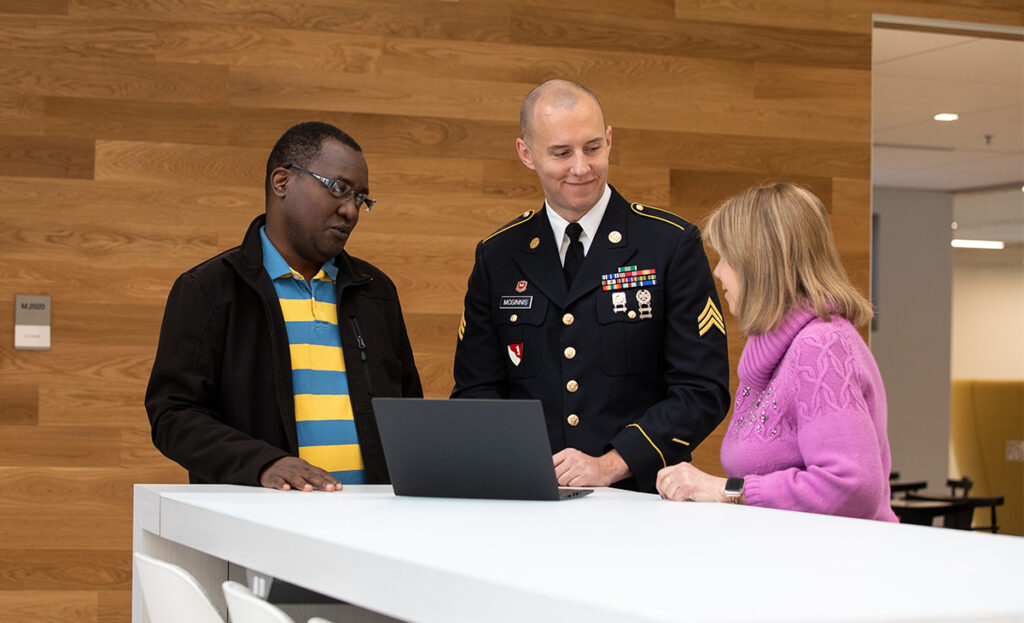 A service member in uniform and in conversation with colleagues