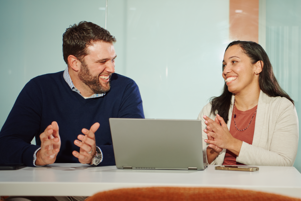 Photo of male and female employees laughing with a laptop