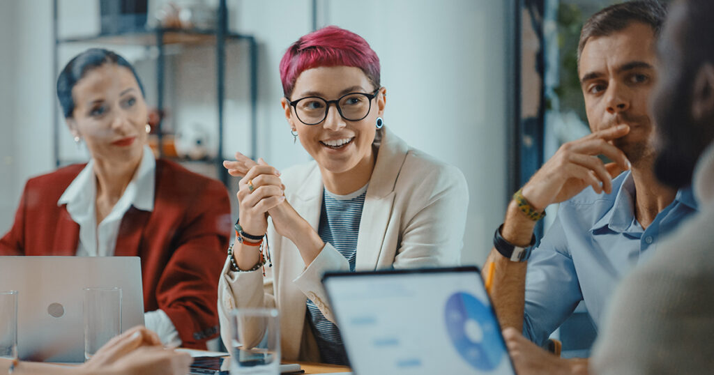 Photo of woman with pink hair laughing during a meeting