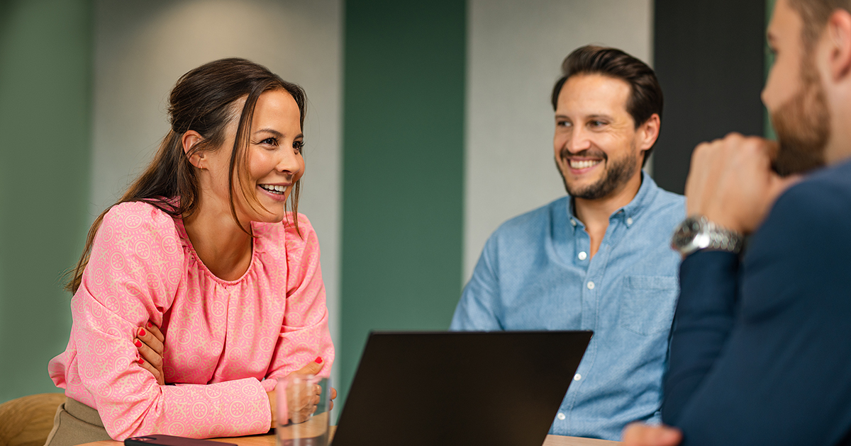 BMS woman employee and man employee sitting around conference room table collaborating.