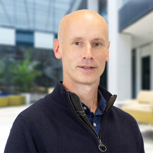 BMS employee Padraig Landers in a dark sweater, standing in an office setting